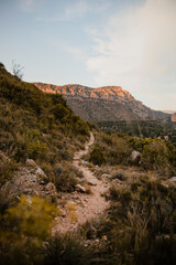 Obraz premium Empty winding hiking trail leading through rugged hills and dramatic mountain scenery. Natural outdoor landscape representing adventure travel, exploration and connection with nature.