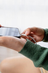 Close-up of woman hands plugging USB cable into smartphone. Symbolizing battery charging, power supply, mobile technology and daily device usage.