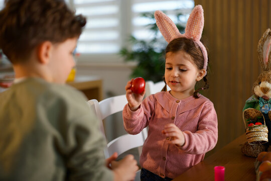 Little girl showing red easter egg to her brother