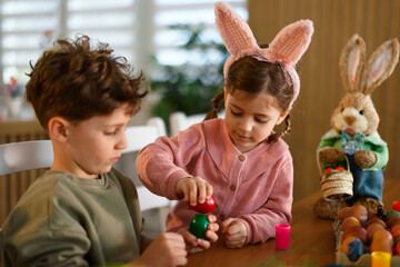 Naklejka premium Kids decorating colorful easter eggs at home