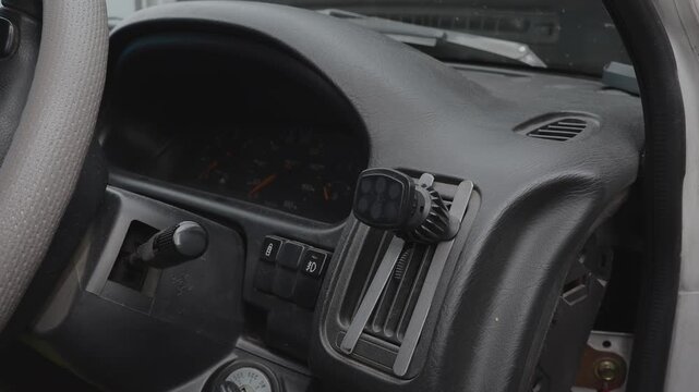Hand Attaching a Smartphone to a Magnetic Car Phone Mount on the Dashboard