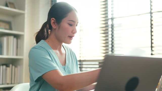 Female healthcare professional reviewing medical documents at desk with laptop in clinic office, administrative medical workflow, patient record management and modern healthcare documentation concept.