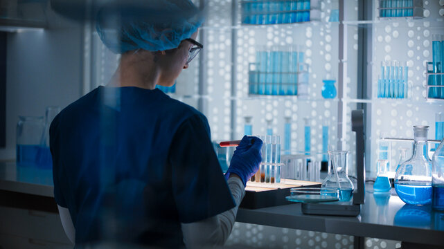 Female researcher in protective wear sorting samples and vials for testing