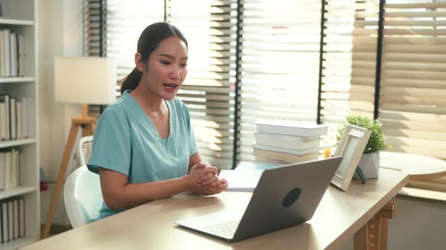 Female healthcare professional reviewing medical documents at desk with laptop in clinic office, administrative medical workflow, patient record management and modern healthcare documentation concept.