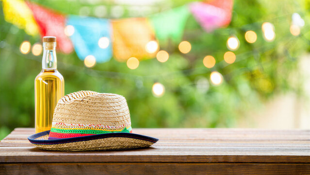 Mexican holiday festive setup with sombrero on wooden table colorful papel picado decorations tequila bottle with lime outdoor Cinco de Mayo celebration vibrant Mexican cultural atmosphere copy space