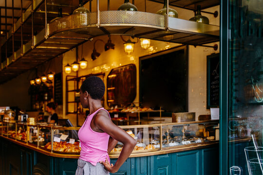 Independent Black woman standing with back turned in stylish cafe interior