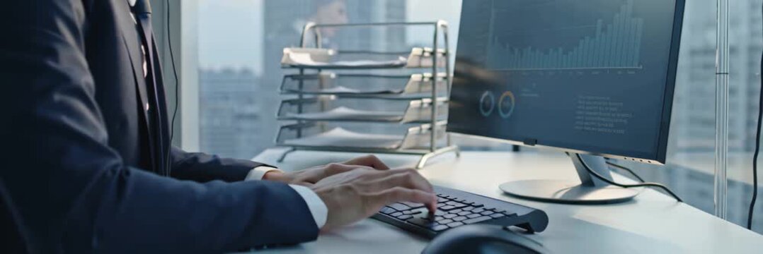 Businessman working on computer in modern office workplace with city view, professional technology workflow concept in wide banner format.