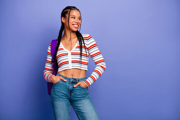 Young chic student model smiles in striped cardigan jeans with purple backpack against blue...