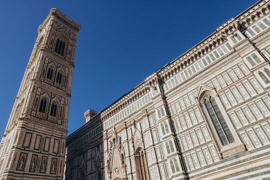 Giotto's Campanile and Duomo di Firenze facades under clear blue sky, capturing historic renaissance architecture in Florence, Italy