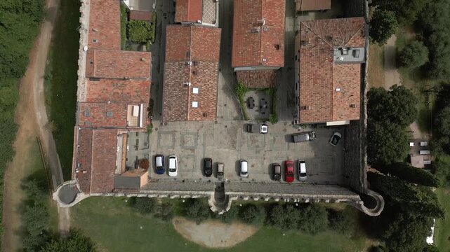 Drone nadir view over castle of Moniga del Garda courtyard, straight down camera glides above terracotta roofs cars and narrow lanes inside the fortress walls