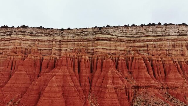 Visitors explore a canyon with large red rock formations. The rocky layers display different colors and patterns from erosion. The view captures the vastness of the canyon.