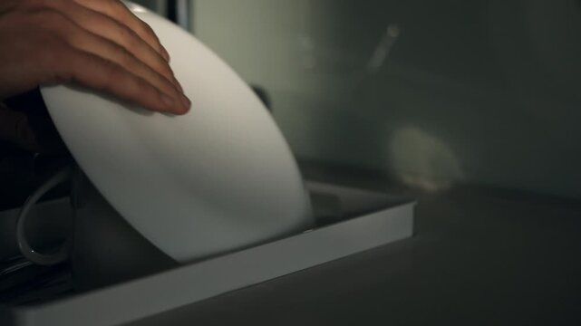 Hand doing the dishes at sink and placing plate on drying rack