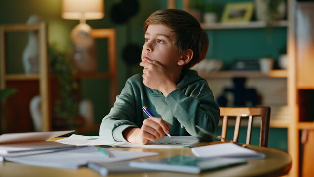 Thoughtful boy studying lesson writing notebook home closeup. Schoolboy learning