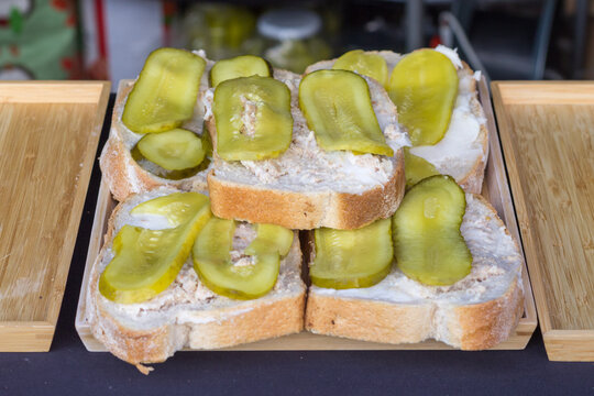 Kanapki ze smalcem i og&oacute;rkiem kiszonym na kromkach chleba, tradycyjna przekąska kuchni polskiej na tacy, proste jedzenie.