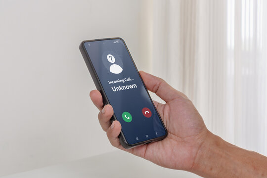 Incoming call from unknown person. Hand holding a smartphone with an incoming call from an unknown number on the screen.