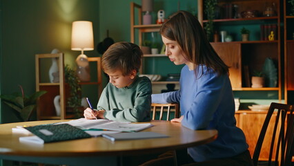 Fototapeta premium Woman tutor supervising pupil learning homework home. Mother supporting student