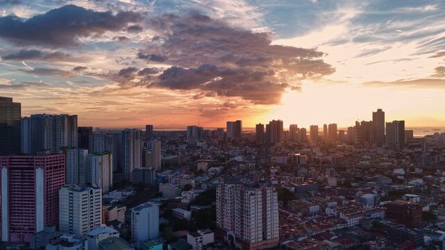 Aerial drone glides beside clustered Makati CBD skyscrapers revealing rooftop details and construction cranes under diffused overcast light with distant mountains visible along the eastern horizon
