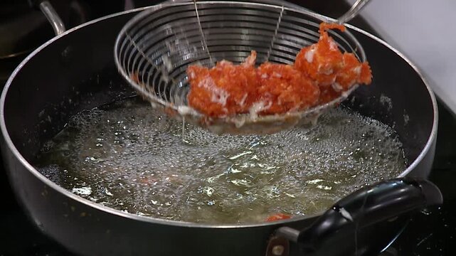 Lifting crispy fried mozzarella sticks from hot oil with metal strainer