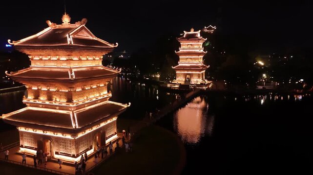 Illuminated pagodas at hoa lu ancient capital on a lake at night in ninh binh, vietnam, aerial view