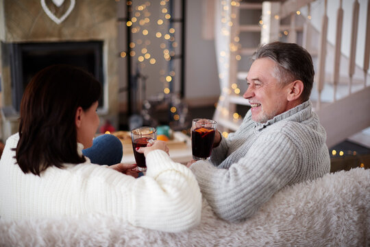 Happy mature couple with hot drinks in living room