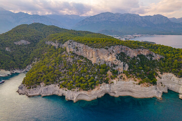 Aerial drone view of rocky Mediterranean coastline with cliffs and pine forest near Kemer Turkey