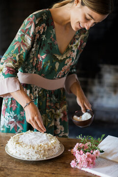 Smiling young woman garnishing home-baked cake