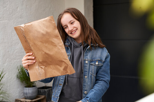 Girl standing in front of house, happy to receive a parcel