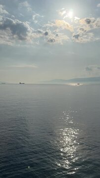 Vertical 4K static shot of a small boat sailing halfway across the sea horizon. High-quality 4K footage with copy space, ideal for travel backgrounds and social media stories.