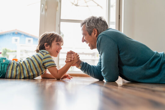 Father and son lying on the floor at home arm wrestling