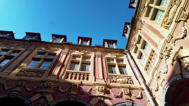 Tilt up shot of the inner courtyard of the Old Stock Exchange in Lille, showcasing ornate Flemish Renaissance architecture under a clear blue sky.