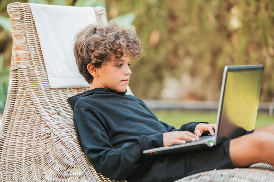 Relaxed boy using laptop on lounge in garden