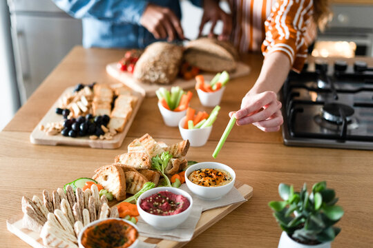 Couple preparing dinner party, hand garnishing dips