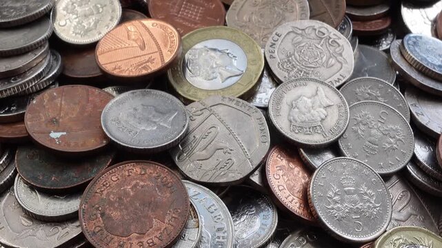 Slow camera movement over pile of United Kingdom coins seamless loop