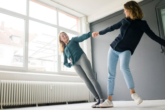 Two young women supporting each other playfully