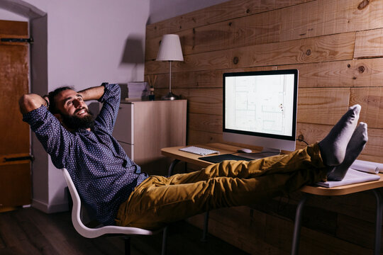 Young happy architect after finishing a new project at home at night