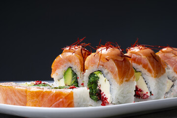 Sushi roll with salmon, tobiko caviar, cheese, and avocado on a plate. © 0990930308