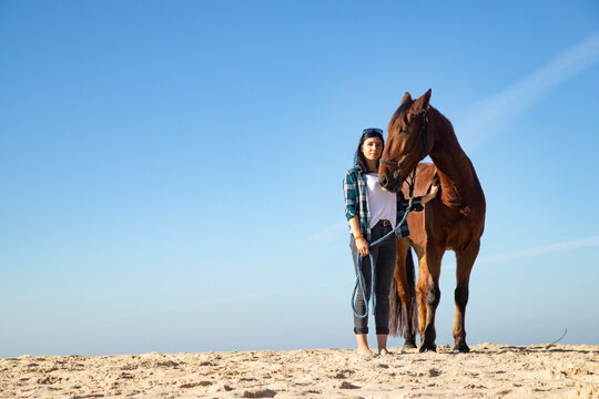 Woman with horse standing in sand