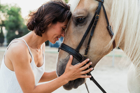 Woman head to head with riding horse