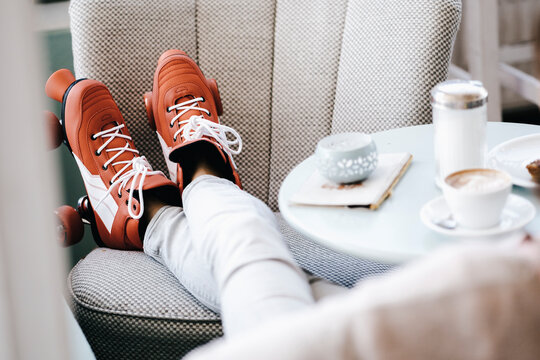 Woman wearing roller skates sitting in a cafe, legs up