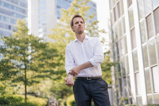 Portrait of confident businessman in the city rolling up his sleeves