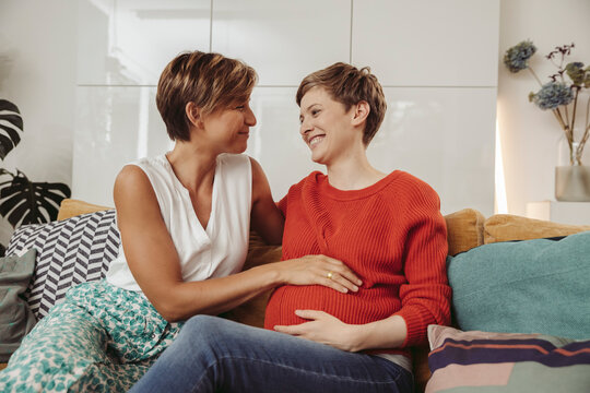 Happy lesbian couple touching belly of the expectant mother