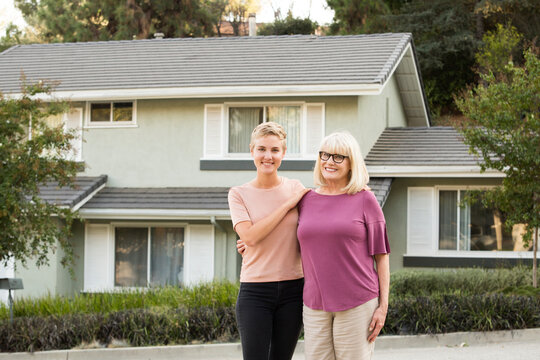 Portrait of smiling woman with mother in front of a house