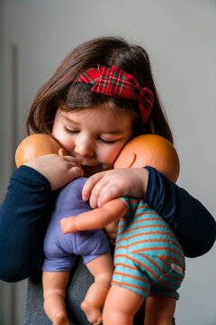 Close-up of cute girl embracing her dolls at home