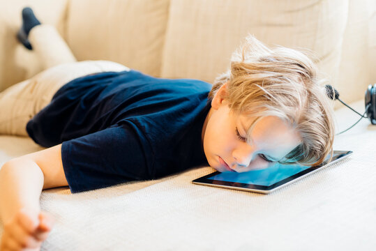 Boy lying on tablet on couch taking a nap