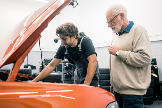Car mechanic talking to client in workshop