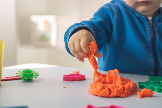 Hand of baby girl taking modeling clay, close-up