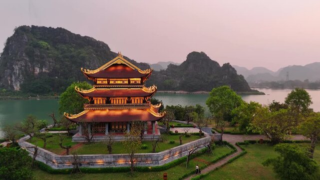 Aerial view of hoa lu ancient capital showing an illuminated vietnamese temple near the water at dusk in ninh binh