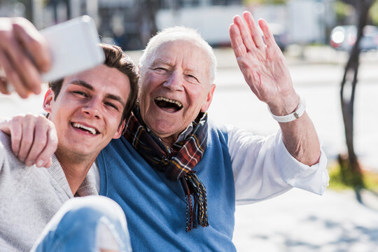 Happy senior man and adult grandson taking a selfie