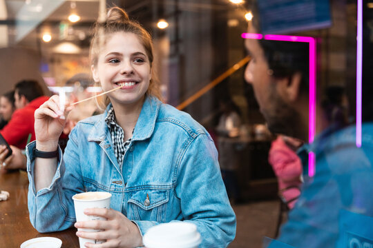 Portrait of smiling young woman in a coffee shop looking at young man