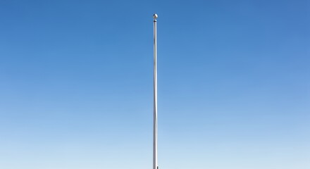 Tall Metal Flagpole Standing Against Clear Blue Sky in Outdoor Setting